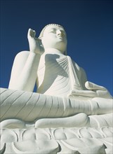 SRI LANKA, Mihintale, Angled view of large white seated Buddha seen from below looking up.
