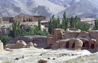 CHINA, Xinjiang, Turpan, View over the Ancient ruins in desert landscape toward distant buildings