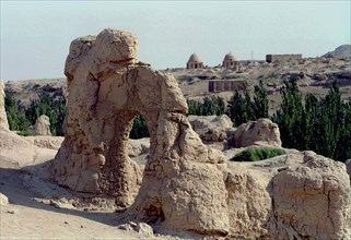 CHINA, Xinjiang, Turpan, View over the Ancient ruins in desert landscape toward distant buildings