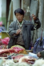 CHINA, Tibet, Lhasa, Outdoor butcher weighing Yak meat