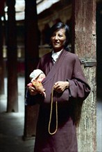 CHINA, Tibet, Lhasa, Portrait of father with small child tucked in his clothing outside the Jokhang