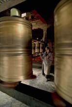 CHINA, Tibet, Lhasa, Jokhang Temple. Worshipper walking clockwise spinning prayer wheels with