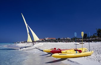 CUBA, Varadero, View along golden sandy beach with kayaks and sail boats at the waters edge