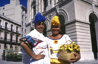 CUBA, Havana, Two smiling women wearing brightly coloured head scarfs standing in the square