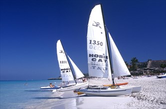 CUBA, Varadero, View along white sandy beach with sail boats at the waters edge