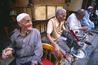EGYPT, Cairo , Group of men smoking sheesha water pipes and drinking tea in an ahwa or coffee house