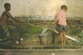 BANGLADESH, Chittagong, Shamshangar, Two young boys drawing water from rowerpump.