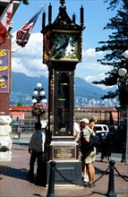 CANADA, Vancouver, Gastown, The Gastown Steam Clock with people reading the inscriptions around the