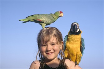 USA, Florida, Fort Lauderdale, Portrait of a young girl with yellow and blue Parrot on her shoulder
