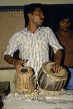 BANGLADESH, Kamalganu, Young man playing tabla drums.