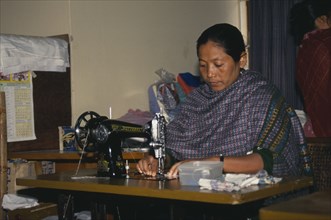 BANGLADESH, Dhaka, Tribal lady working at sewing machine.