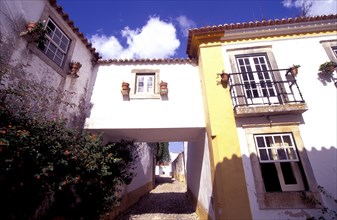 PORTUGAL, Leiria, Obidos, Cobbled street with traditional housing and archway