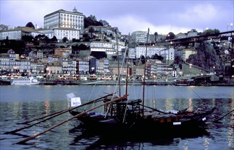 PORTUGAL, Porto, Oporto, View over boats moored in the port toward the city illuminated at dusk