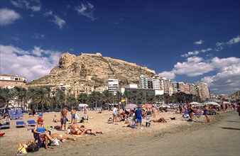 SPAIN, Alicante, Busy beach scene with clifftop castle beyond