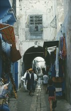 TUNISIA, Tunis, Market scene.  Men and children walking through narrow cobbled street lined with