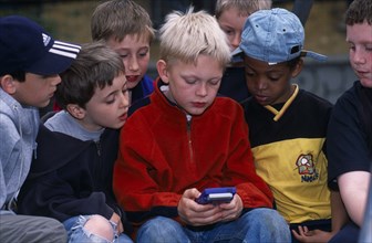 GAMES, Games, Boy playing with his Gameboy computer game whilst being watched by his friends