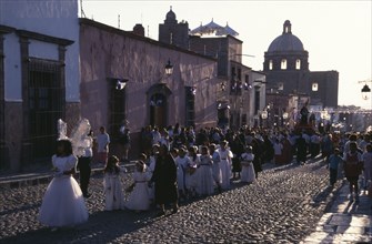 MEXICO, San Miguel de Allende, Easter Procession down cobbled street with children dressed in white