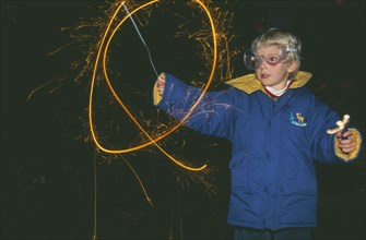 ENGLAND, Oxfordshire, Festivals, Young boy wearing protective eye glasses making circular light