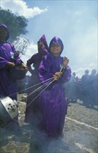 GUATEMALA, Antigua, Easter procession with boy in robes releasing incense