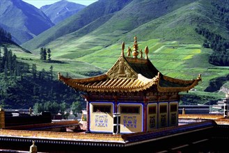 CHINA, Gansu, Xiahe, Golden roofed Labrang Monastery and green hillsides beyond