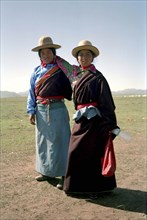 CHINA, Gansu, Xiahe, Full length portrait of two sisters travelling on foot to local festival