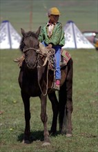 CHINA, Gansu, Xiahe, Young boy dressed as Genghis Khan riding a pony