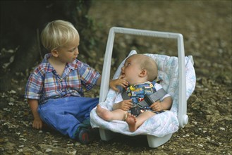 FRANCE, Dordogne, Young boy sitting with his baby brother in a baby carrier