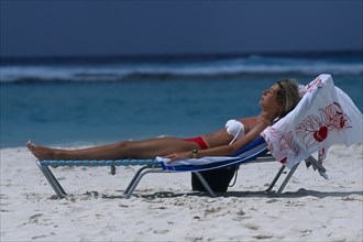 WEST INDIES, Barbados, Worthing, Girl sunbathing on a sun bed on Sandy Beach