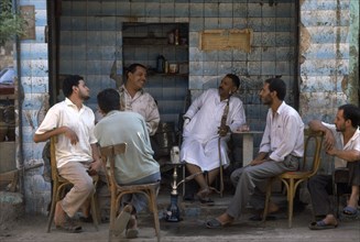EGYPT, Cairo, Group of men talking and smoking hookah in a tea shop.