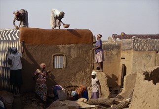 BURKINA FASO, Tiebele, Group of women preparing house front for decorative painting in traditional