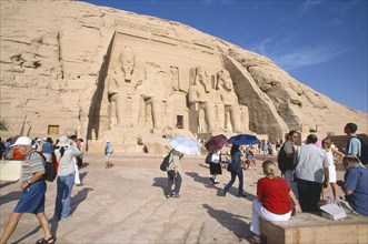 EGYPT, Nile Valley, Abu Simbel, Sun Temple of Ramses II.  Tourists outside entrance flanked by four