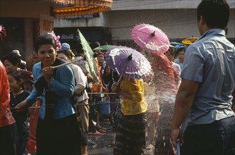 THAILAND, North, Chiang Mai , Girls with umbrellas being sprayed with water on the street during