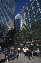 ENGLAND, London, Canary Wharf.  Businessmen and women drinking at outside tables with glass fronted