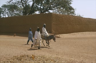 NIGERIA, Kano, Street scene with two men walking beside a man on a donkey
