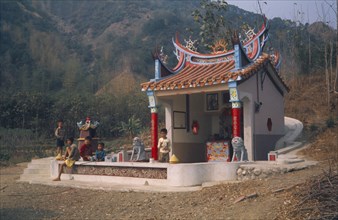 TAIWAN, Mai Nung, Colourful ancestors shrine with children sitting in front