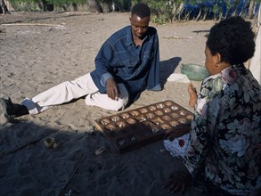 TANZANIA, Pangani, Fishing village with a couple playing an age old game called Mbao