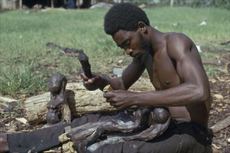 TANZANIA, Craft, Makonde man carving traditional wooden sculpture.