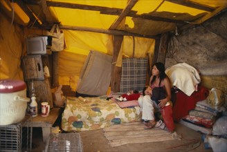USA, New Mexico, Navajo Reservation summer camp.  Woman and children inside tent watching