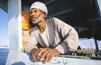 EGYPT, Nile Valley, Luxor, Man leaning on side of ferry.