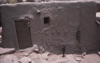 MALI, Dogon village, Detail of exterior wall and door of chiefs house with small child standing