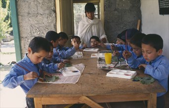 PAKISTAN, Northern Areas, Sherqillah, Female teacher at boys school with pupils in art class.