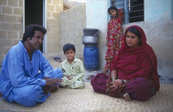 PAKISTAN, Sindh Province, Ibrahim Hyderi, Family sitting in the courtyard of their home.