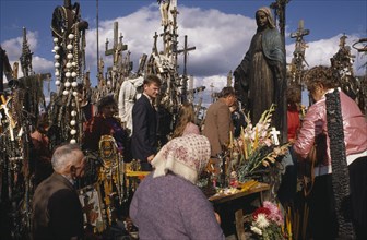 LITHUANIA, Hill of Crosses, People praying at ancient pilgrimage site near Siaulial.