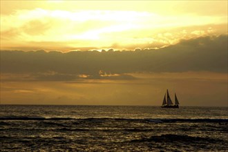 USA, Hawaii, Honolulu, Sunset over the sea with passing sail boat