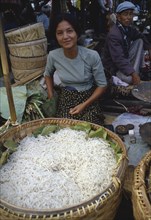 MYANMAR, Markets, Young woman selling noodles on market stall near Inle Lake.