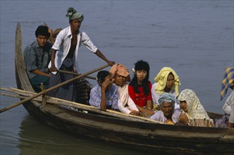 MYANMAR, Irrawaddy River, Man scissor rowing wooden canoe with passengers.