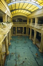 HUNGARY, Budapest, Gellert Baths.  Interior with bathers in swimming pool lined with carved pillars