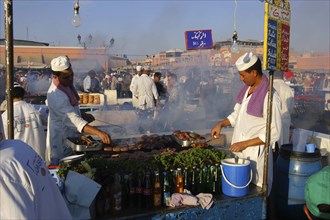 MOROCCO, Marrakech, Djemaa El Fna. Market stall with two men cooking food
