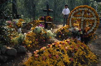 MEXICO, Michoacan State, Patzcuaro, Graves in Tzurumutaro Cemetary decorated with flowers fruit and