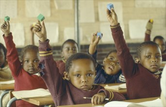SOUTH AFRICA, Gauteng, Soweto, Classroom scene.  Young pupils raising hands.